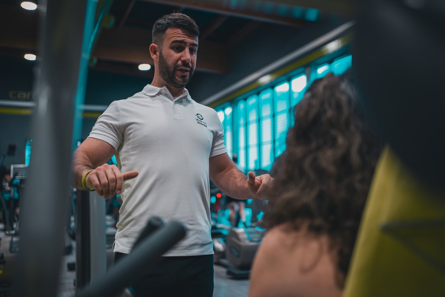 Personal trainer demonstrating an exercise to a client in a gym.