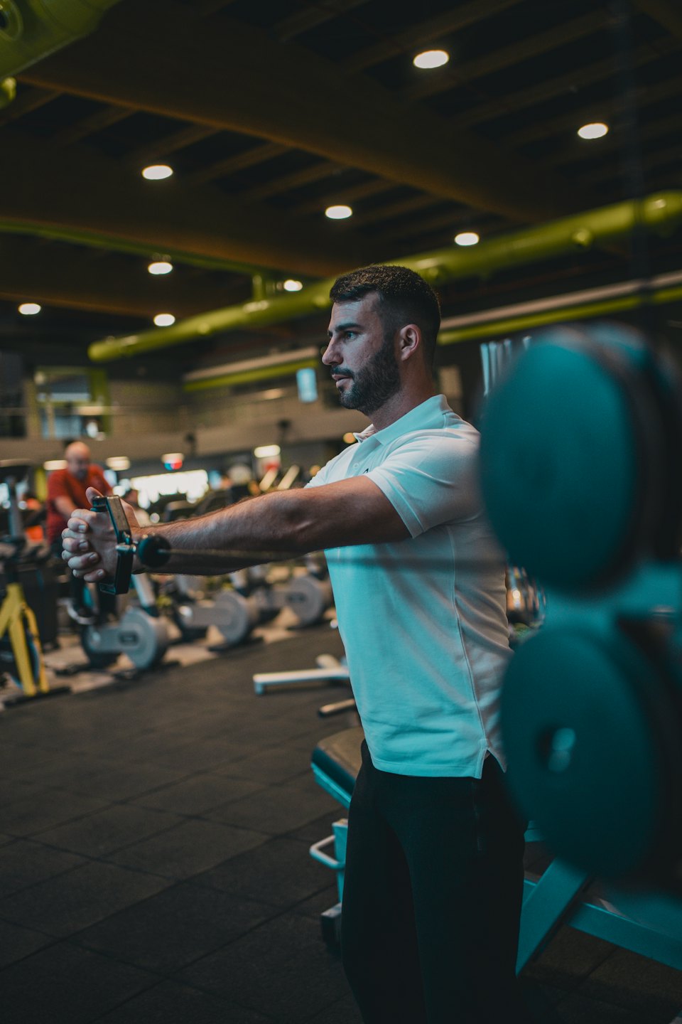 Man performing strength training with cable machine handles.